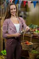 Smiling woman clicking picture of tomatoes in the basket at the grocery store