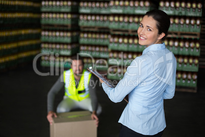 Female factory worker standing with clipboard in factory
