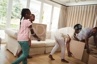 Parents and kids carrying cardboard boxes in living room