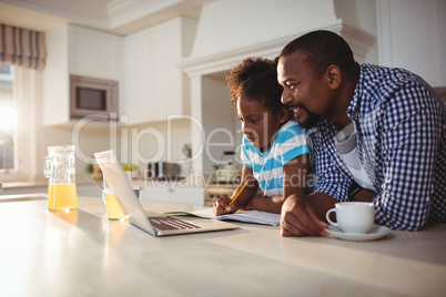 Father and daughter using laptop while having coffee