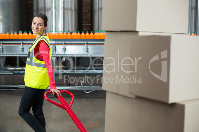 Female factory worker holding trolley of cardboard boxes