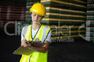 Female factory worker writing on clipboard in factory