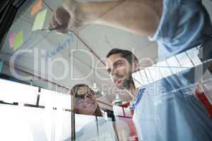 Business executives writing over sticky notes on glass