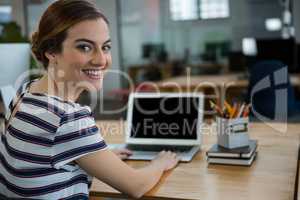 Smiling female graphic designer using laptop