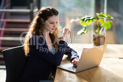 Female business executive using laptop at desk
