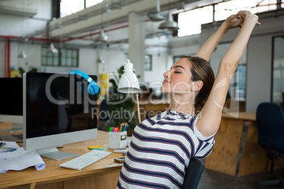 Female graphic designer sitting on chair and stretching her arms