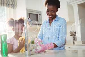 Mother assisting her daughter in cleaning utensils