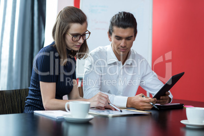 Two business executives discussing over chart at desk