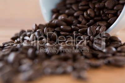 Roasted coffee beans spilling out of cup