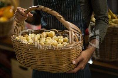 Vendor holding basket of potatoes at the grocery store