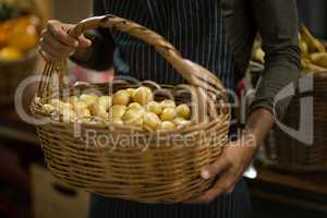 Vendor holding basket of potatoes at the grocery store