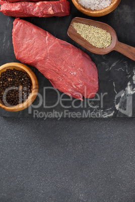 Beef steak, salt and spices on black slate plate