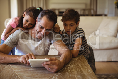 Father and kids using digital tablet in living room