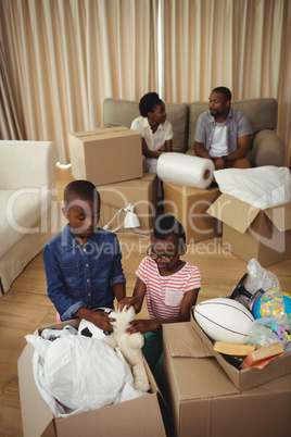 Parents and kids unboxing cardboard boxes in living room