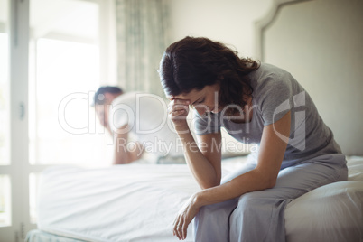 Tensed woman sitting on a bed