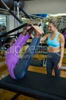 Smiling trainer assisting woman with pilates on reformer