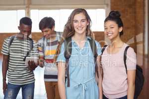 Portrait of schoolgirls standing with classmate with classmates in background