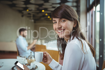 Executive using mobile phone while having coffee in cafÃ?Â©