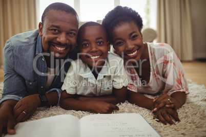 Portrait of parents and son reading a book while lying on a rug