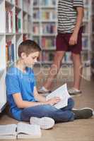 Attentive schoolboy reading book in library