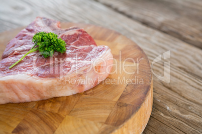 Raw Sirloin chop and corainder leaves on wooden tray against wooden background