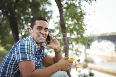 Portrait of executive talking on mobile phone while having banana