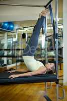 Determined woman performing stretching exercise on reformer