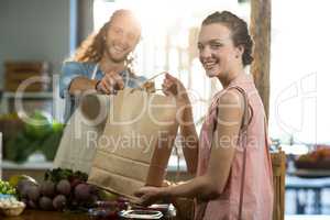 Vendor handing a bag of vegetables to woman at grocery store