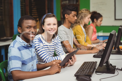 Smiling students studying in computer classroom