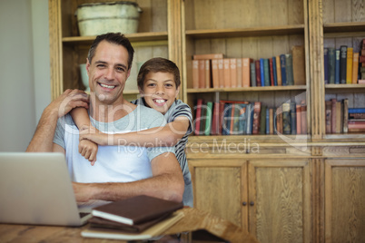 Portrait of father and son using laptop in study room