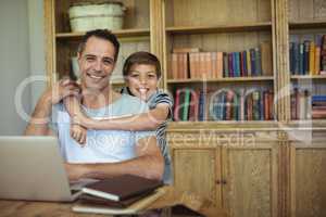 Portrait of father and son using laptop in study room