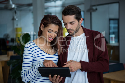 Man and woman discussing over digital tablet