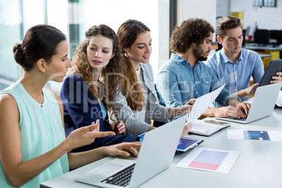 Business team working on laptop and digital tablet in meeting