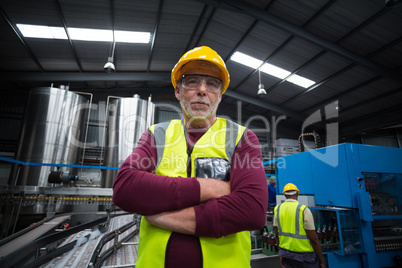 Confident factory worker standing with her arms crossed