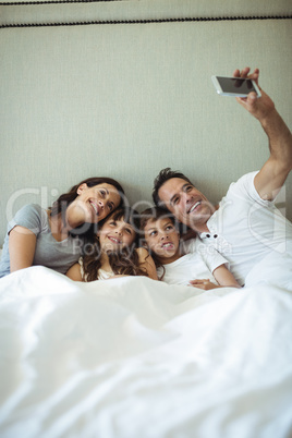 Parents and kids taking a selfie on bed