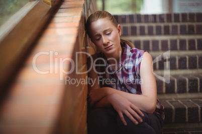 Sad schoolgirl sitting alone on staircase