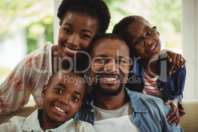 Portrait of parents and kids sitting on sofa in living room