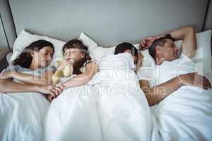 Parents and kids sleeping on bed