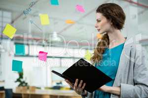 Female executive looking at sticky notes and holding folder