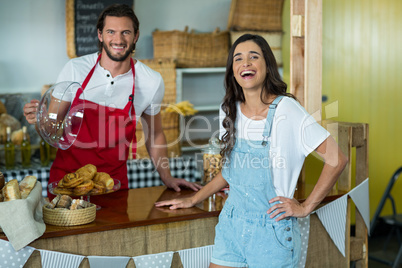 Smiling bakery staff showing snack to the female customer at counter