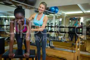 Portrait of trainer assisting woman with wunda chair in fitness studio