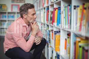 Thoughtful school teacher selecting book in library