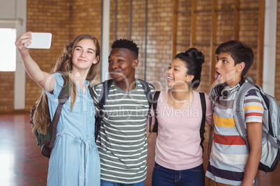 Happy students taking selfie on mobile phone in campus