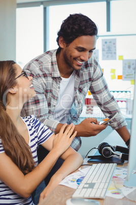 Male and female graphic designers interacting with each other at desk