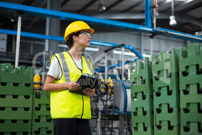 Female factory worker maintaining record on digital tablet