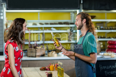 Shop assistant offering olive oil bottle to the customer