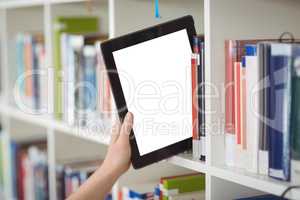 Hand of student keeping digital tablet in bookshelf in library