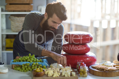 Salesman arranging cheese at counter