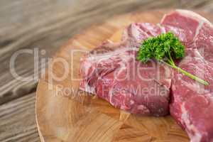 Raw Sirloin chop and corainder leaves on wooden tray against wooden background