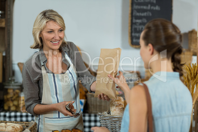 Female customer receiving a parcel from bakery staff at counter
